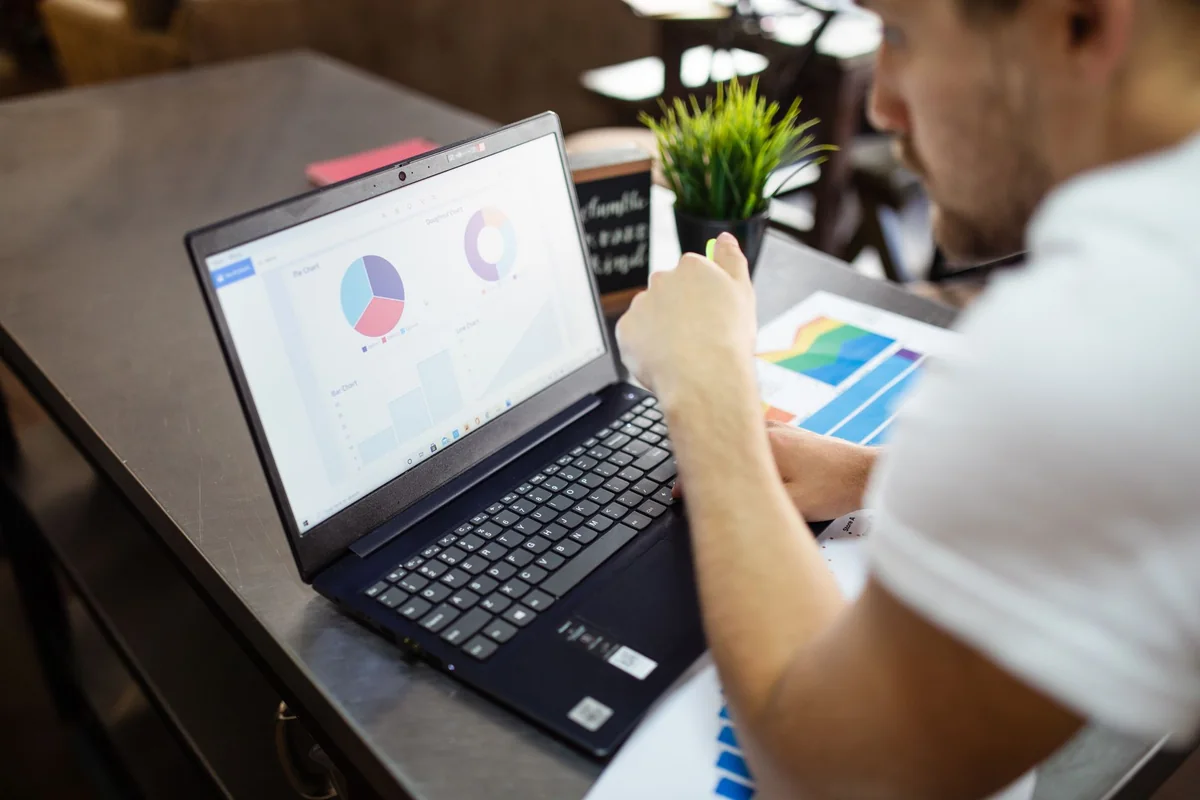 A person reviewing data charts on a laptop, standing in for the pricing algorithm an iBuyer like Opendoor uses