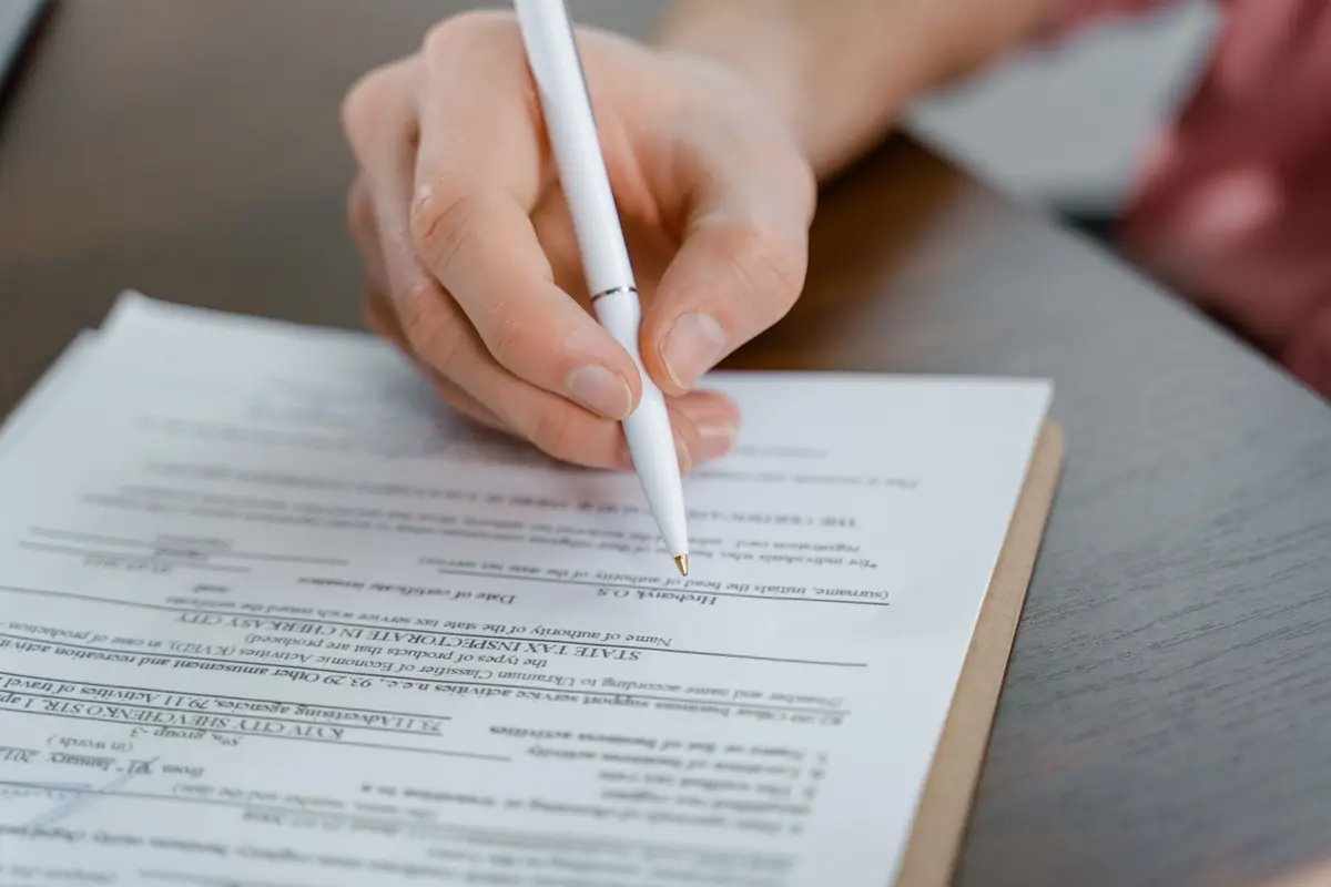 A hand signing closing documents with a pen, the fast certainty a cash home sale in Iowa buys you