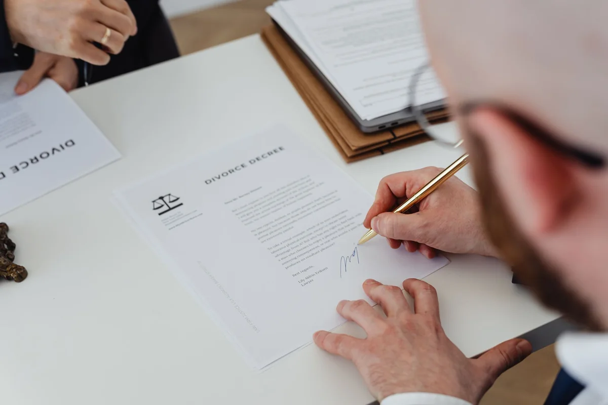 A person signing legal disclosure documents at a table before an Iowa home sale