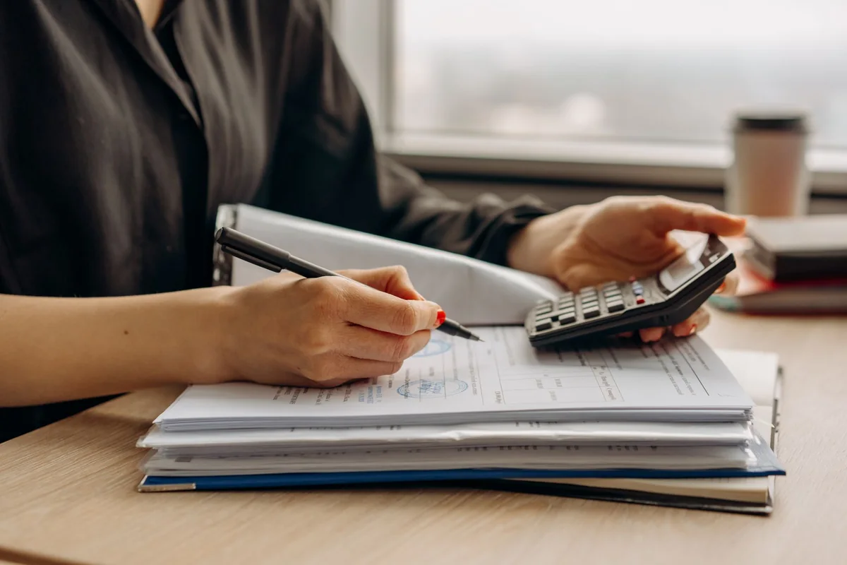 A person reviewing a payoff statement with a calculator, the HOA estoppel figure a title company needs