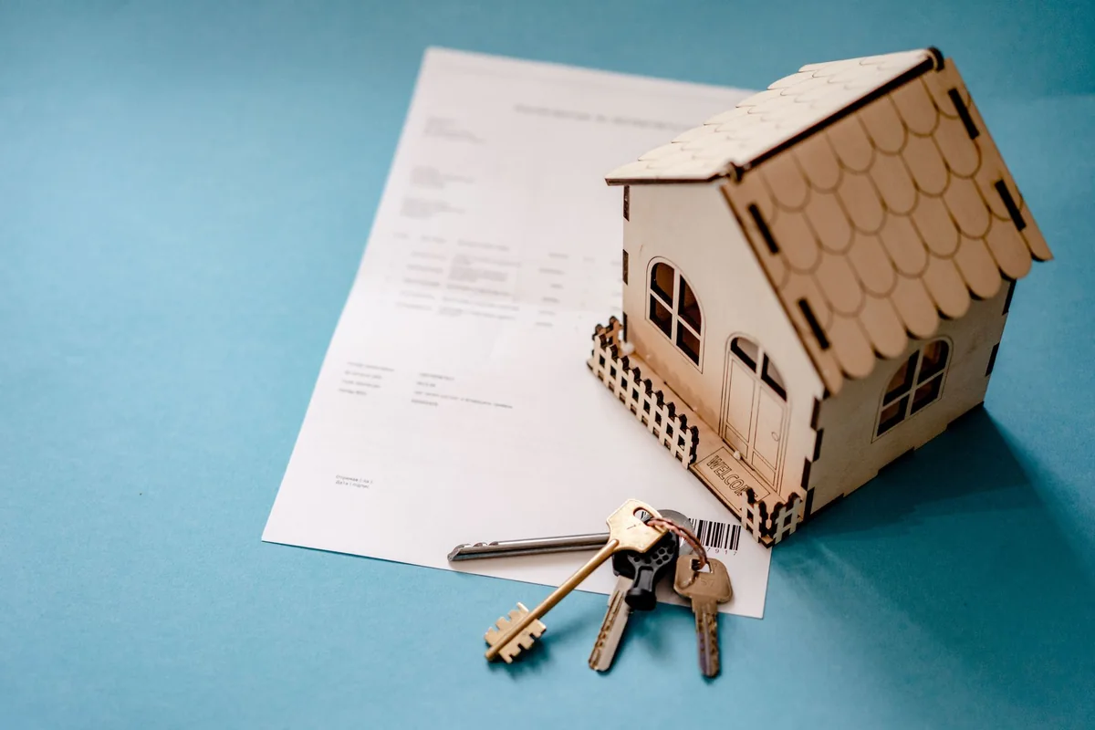 A model house with keys and a contract showing you can sell a house with a lien