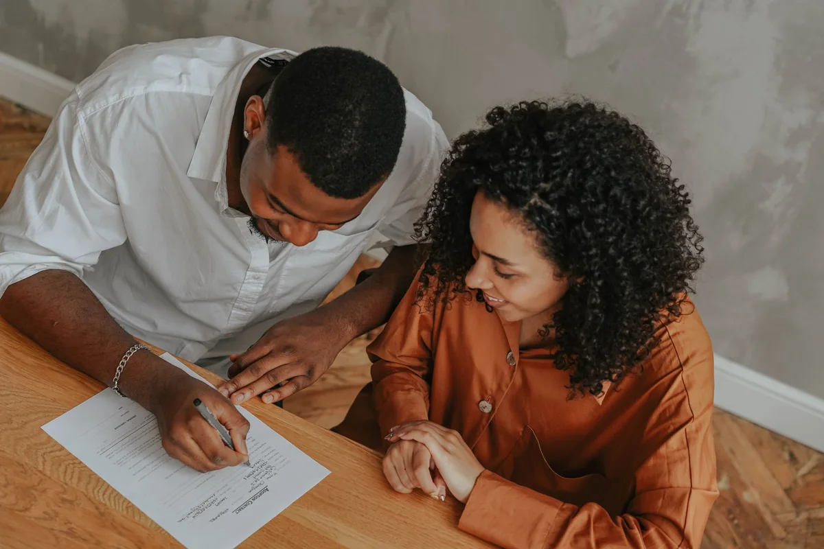 A person signing paperwork at a table, showing that every owner must sign to sell a life estate house