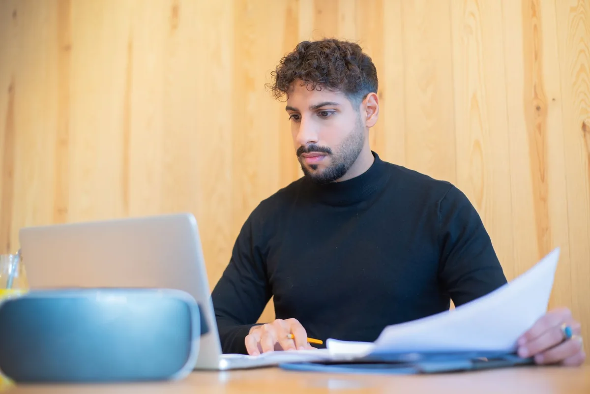 A person reviewing documents on a laptop, checking the Iowa Mechanics Notice and Lien Registry for a mechanic's lien