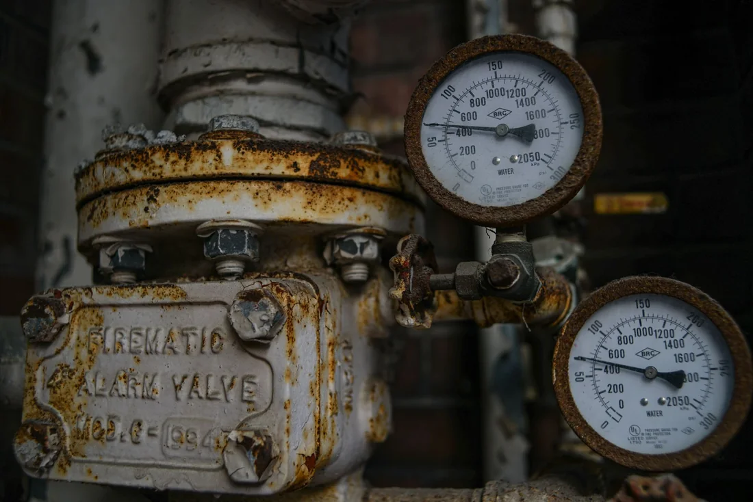 Rusted, aging mechanical fixtures and gauges in an older building, the kind of outdated systems found in Iowa homes that still have knob-and-tube wiring