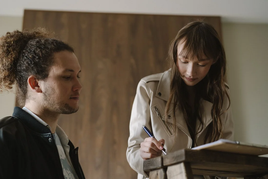A landlord and tenant signing a rental lease at a table, the paperwork behind selling a house with a Section 8 tenant in Iowa