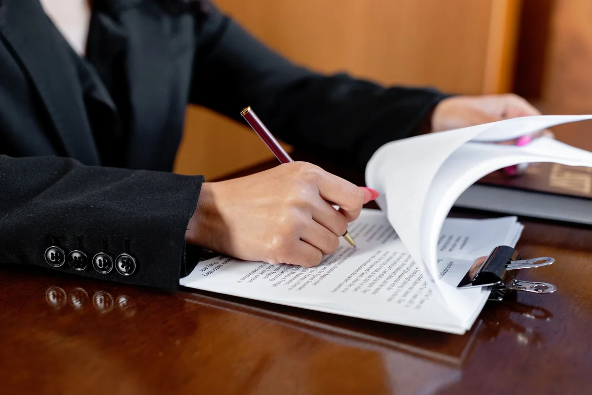 A person reviewing legal contract paperwork at a desk, handling a HAP contract during a home sale