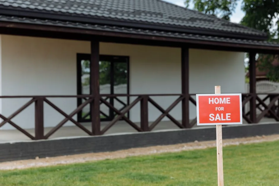 A home-for-sale sign in a front yard, standing for the title question when selling a mobile home in Iowa