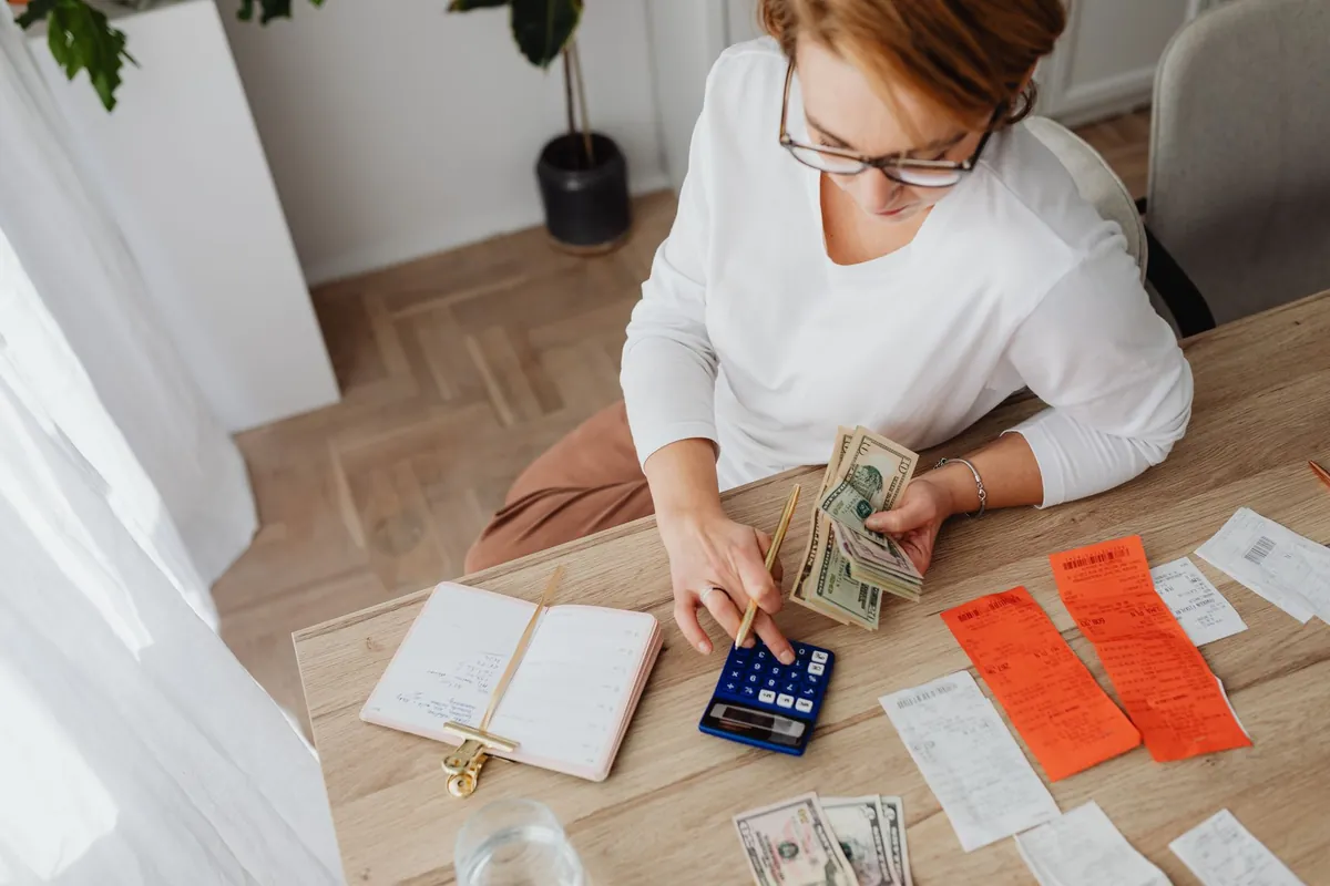 Calculator, cash, and a laptop used to figure the tax basis on a house sale